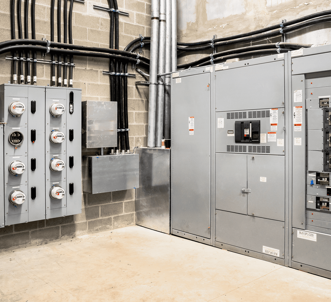 Industrial electrical panels and conduit pipes in a utility room.