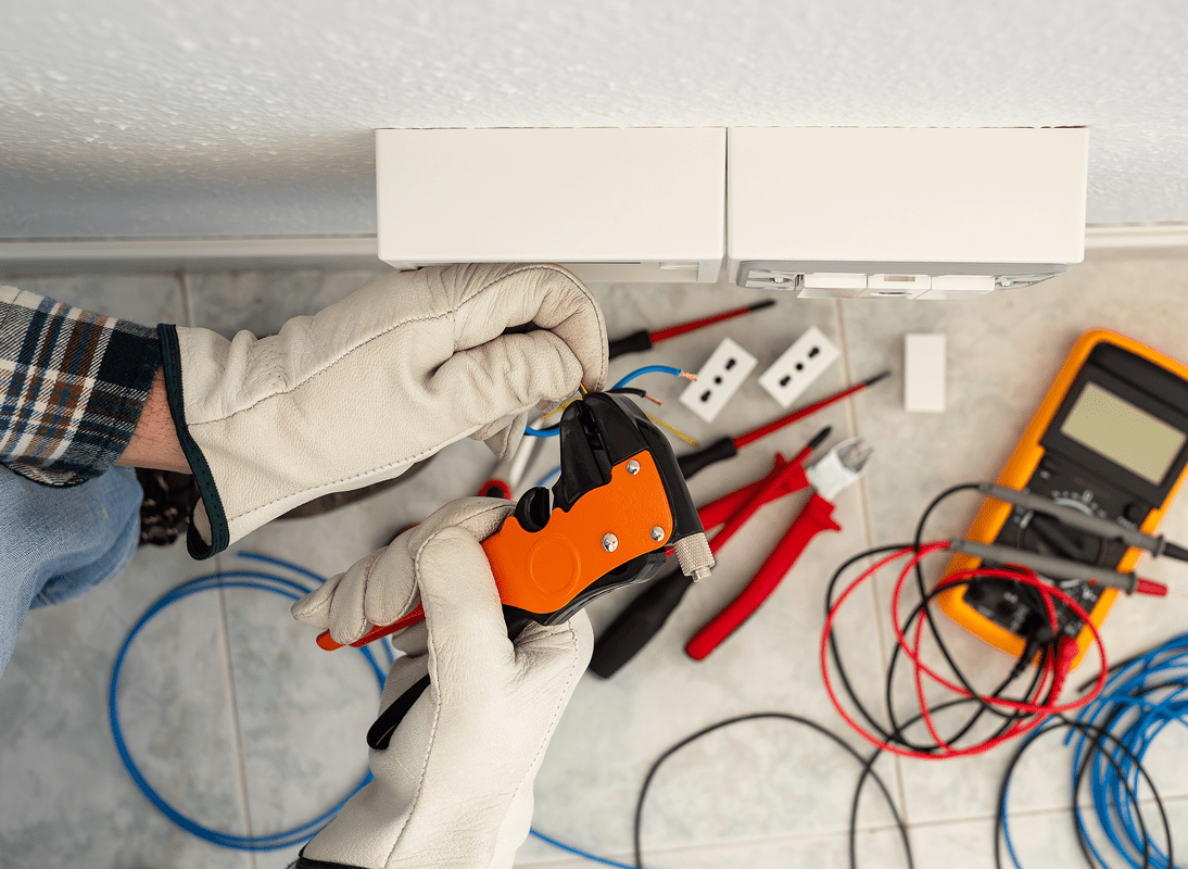 Technician repairing or assembling electronic equipment with various tools on the table.